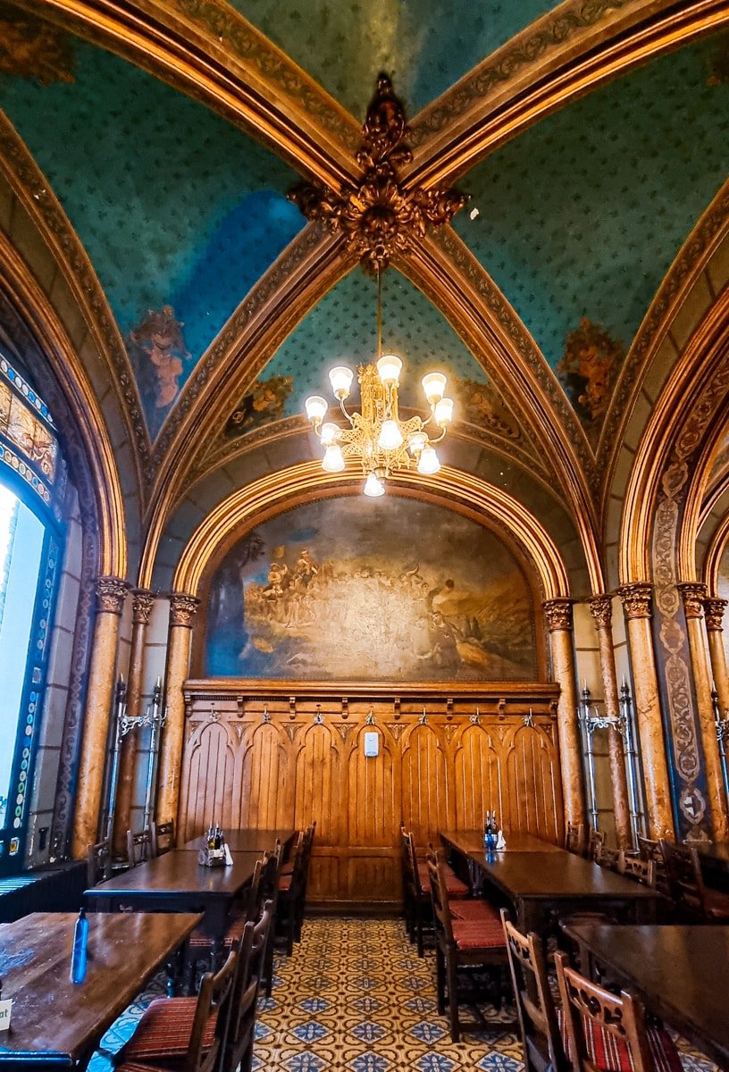 An ornately decorated room with tables and chairs at Caru' cu Bere Bucharest.