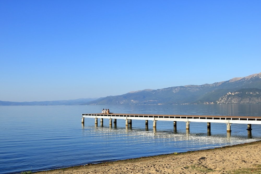 Pogradec in Albania: Ohrid Lake shore with some people and boats in the late summer